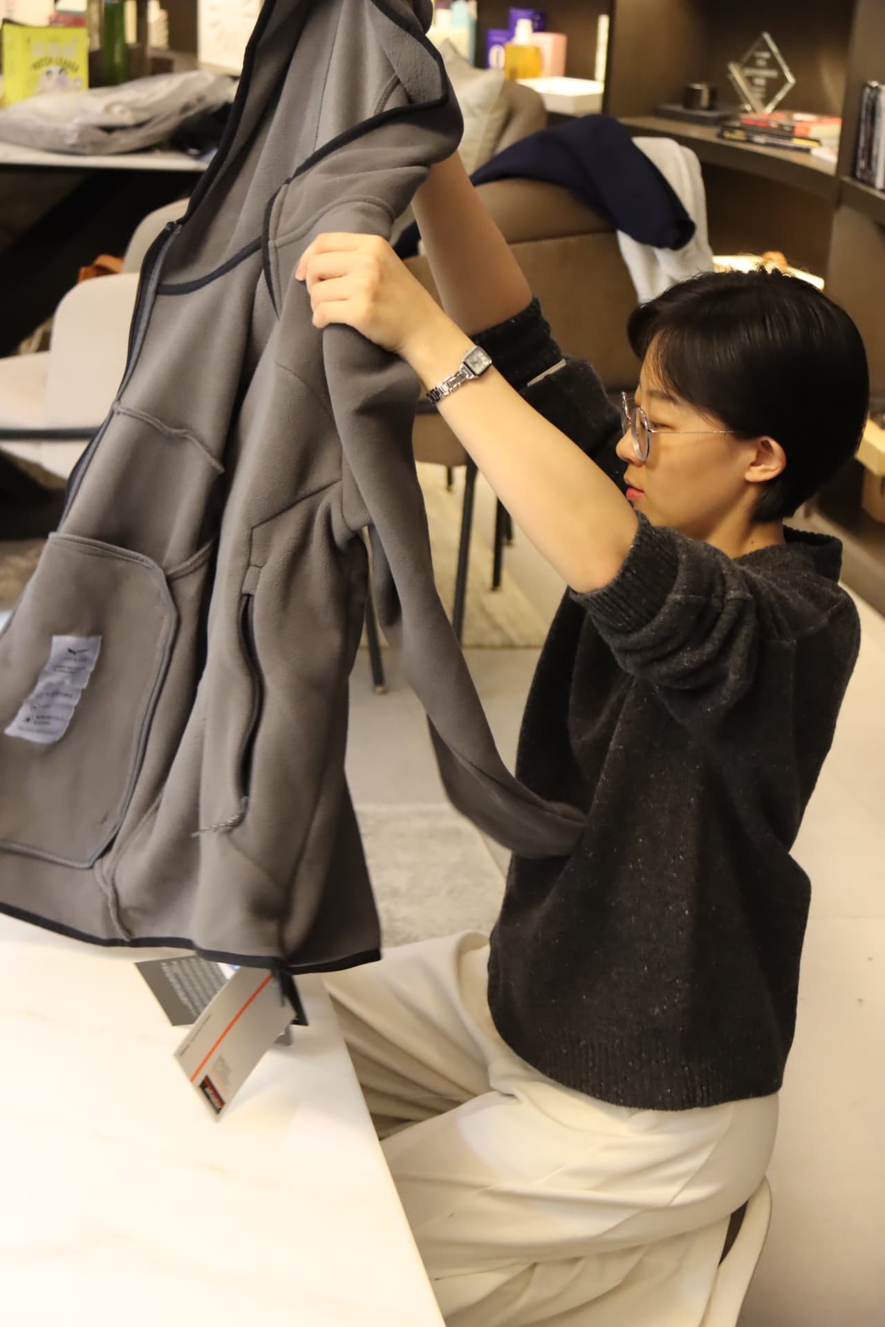 Hand inspecting a heavyweight grey hoodie before packing